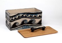 Brottopf 'Dynamo'<br>
Scraffitto in Blau, Weiß, Schwarz.<br>Zwei Wellenbewegungen laufen so ineinander, dass sie ein schwungvoll dynamisches Ganzes ergeben. Die Form des Griffs entspringt dem Muster und liegt wunderbar in der Hand. <br>
Deckel in Eiche, wäre auch in Nussbaum sehr attraktiv. 
Das Scraffitto läuft rund um den Topf. <br>
Allein zur Dekoration benötigt dieser Topf mehr als 4 Arbeitsstunden. <br>
incl. Versand : 320,- €